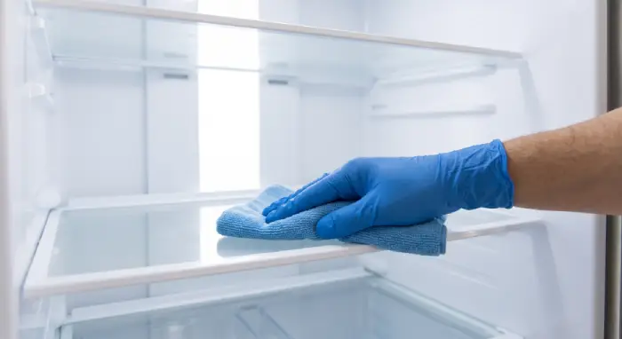 Cleaner wiping down an empty refrigerator during a move-out clean in Ottawa